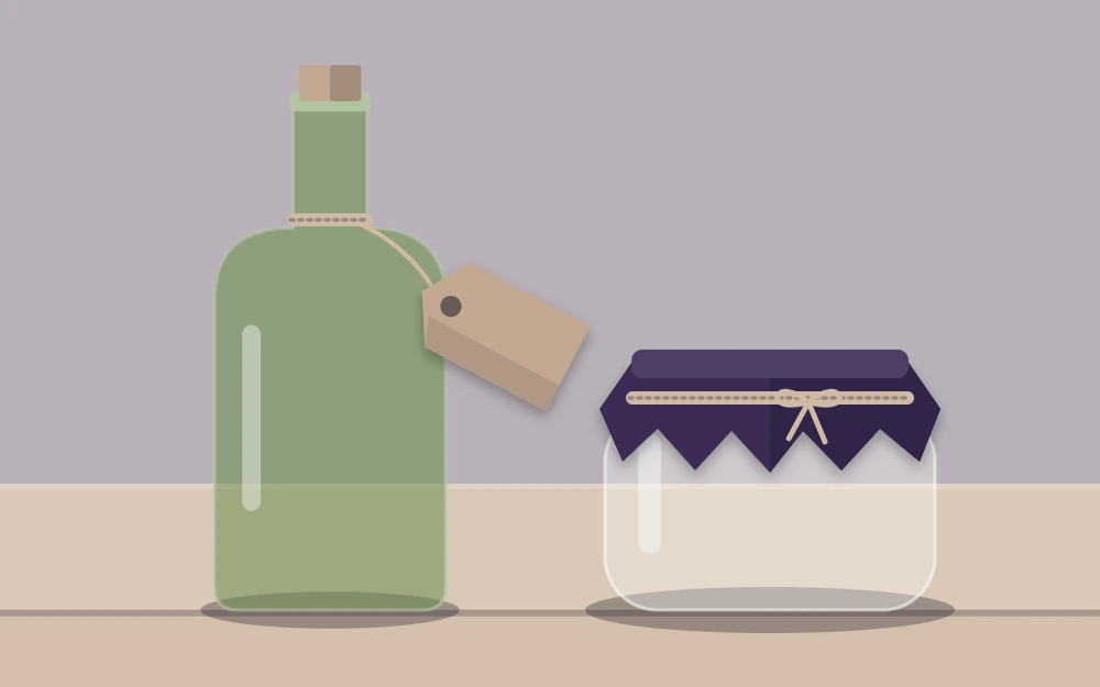 A tall corked bottle with a blank tag beside a short jar with fabric tied over the lid