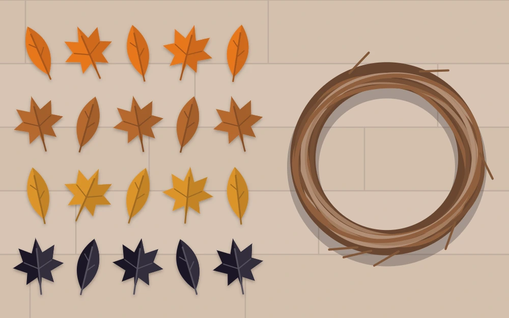Felt and faux leaves in orange, rust, gold and black sorted in rows beside a bare grapevine ring