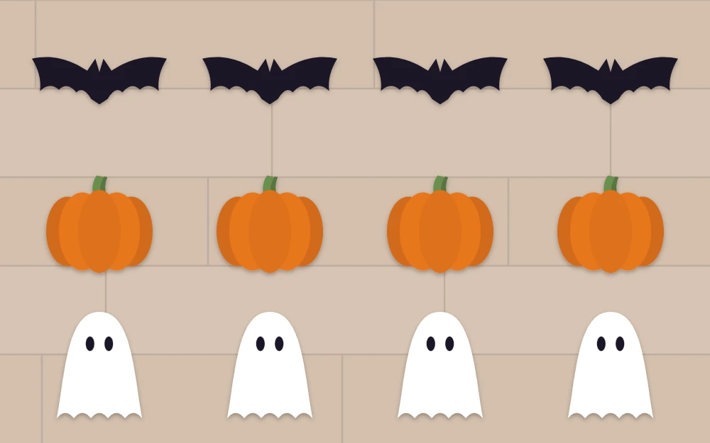 Cut felt bats, orange pumpkins with green stems and white ghosts arranged in rows on a table