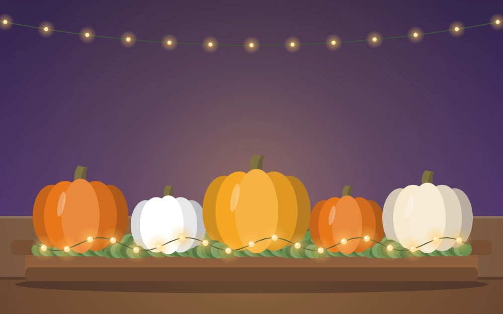 A low tray centerpiece with small pumpkins, moss and tiny lights, seen from the side