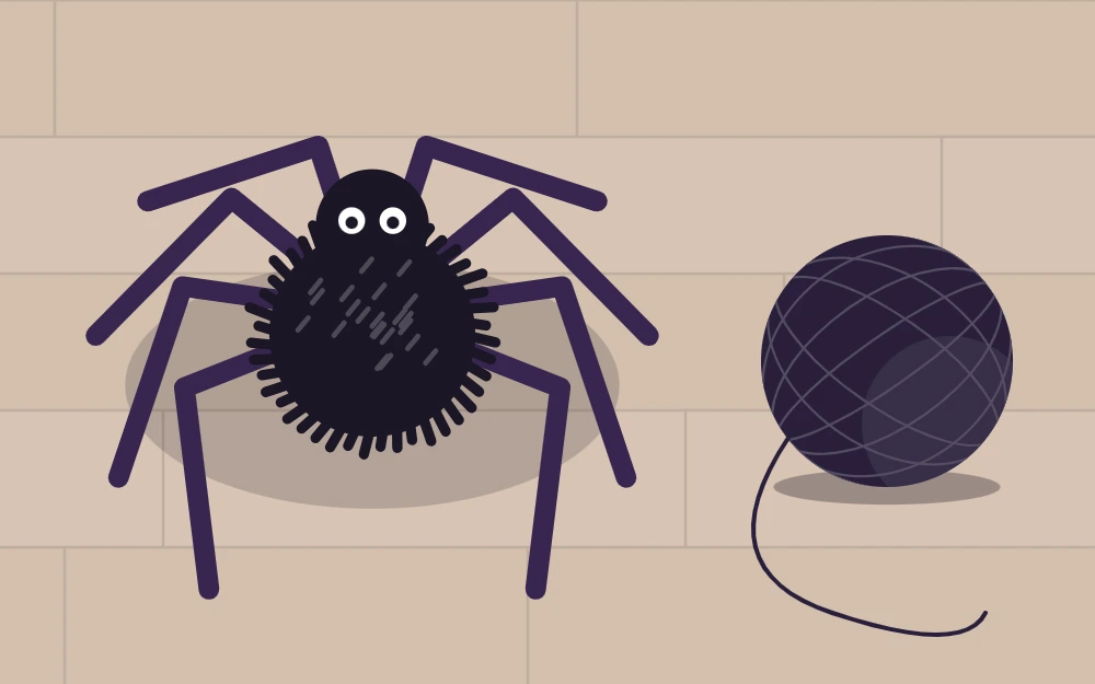 Black pom-pom spider with eight bent chenille-stem legs next to a ball of yarn